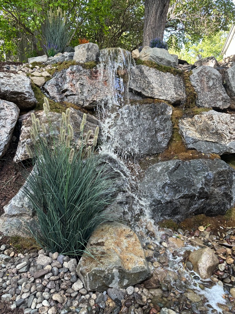 Multi-tier pondless waterfall cascading over natural boulders into river rock