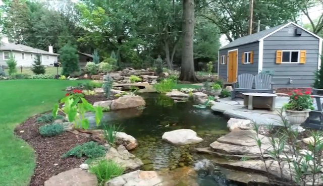 Multi-tier backyard pond and waterfall with a flagstone patio and fire pit