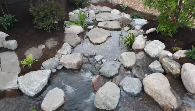 Clear garden stream with flagstone stepping stones and landscape lighting