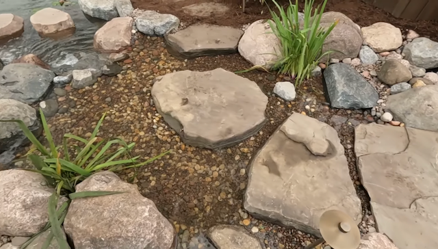 Close view of flagstone stepping stones over a pebble-lined stream